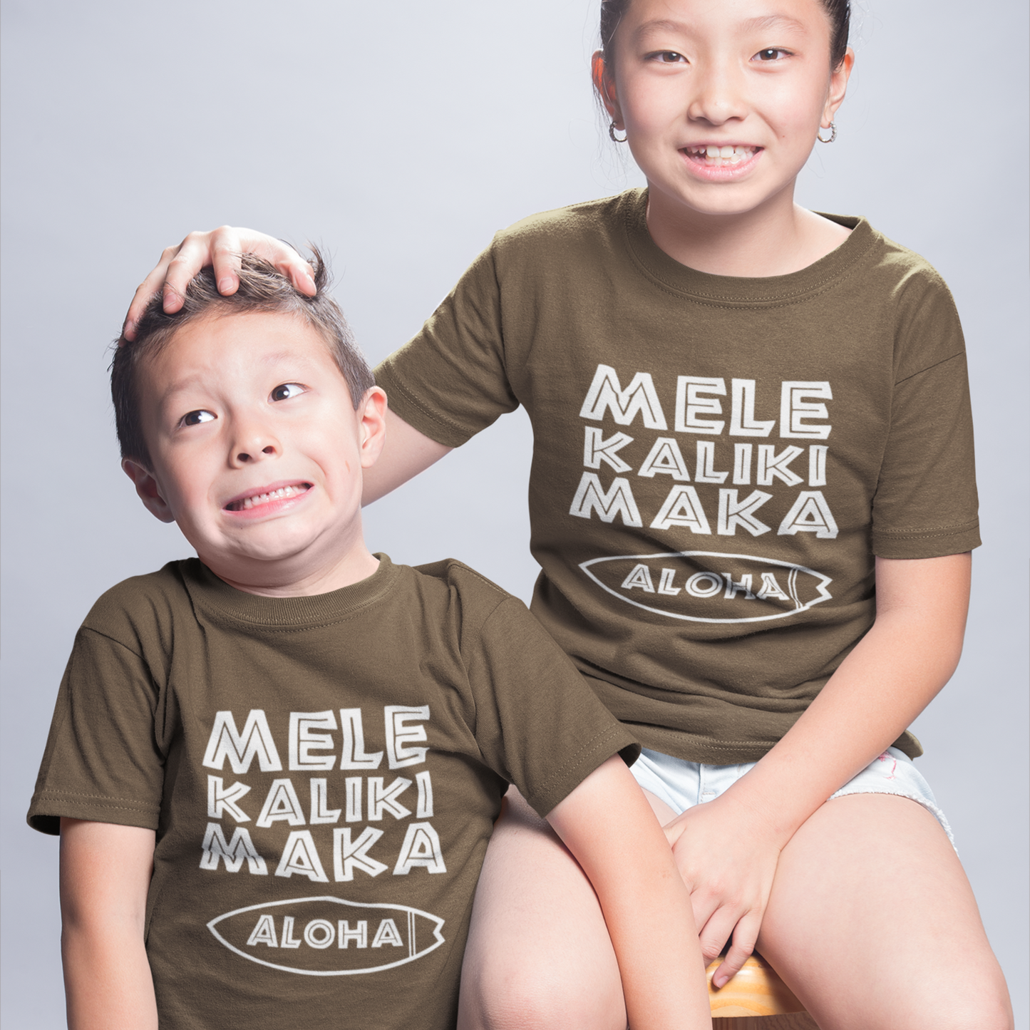 Kids Mele Kalikimaka Christmas T-Shirt with a surfboard hibiscus graphic perfect for holiday celebrations. Holiday Gift Idea! 